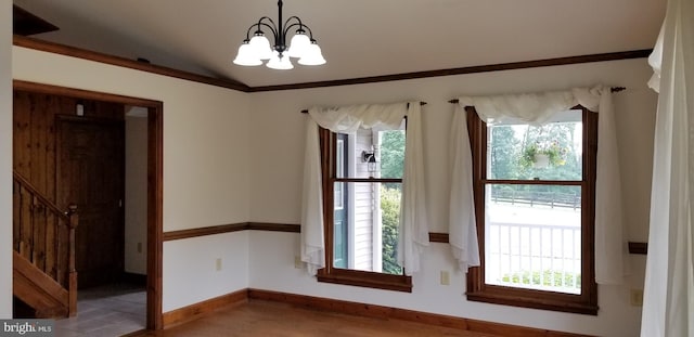 spare room with wood-type flooring, lofted ceiling, and a notable chandelier