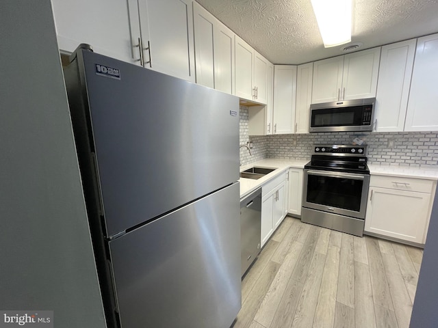 kitchen with stainless steel appliances, sink, and white cabinets