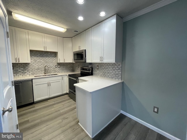 kitchen with stainless steel appliances, sink, decorative backsplash, and white cabinets