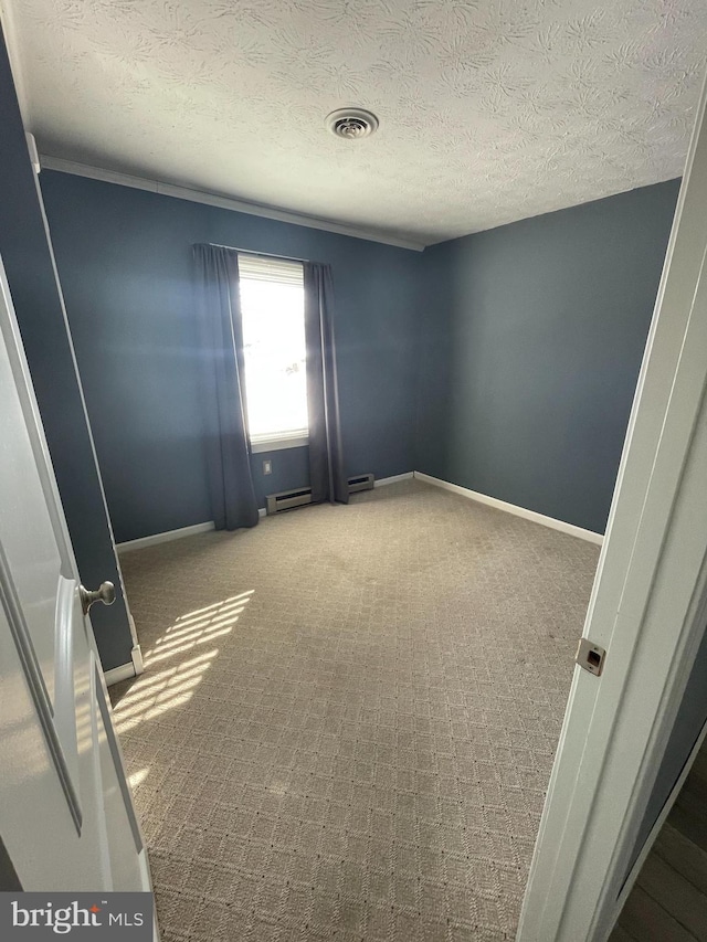 spare room featuring baseboard heating, carpet flooring, and a textured ceiling