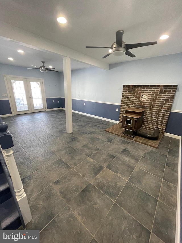 basement featuring a wood stove, ceiling fan, and french doors