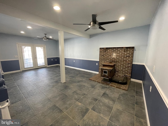 basement featuring a wood stove, ceiling fan, and french doors