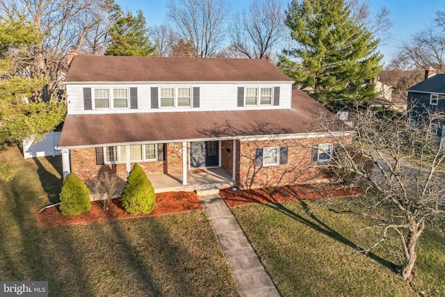 view of front of home with a front lawn, a porch, and brick siding