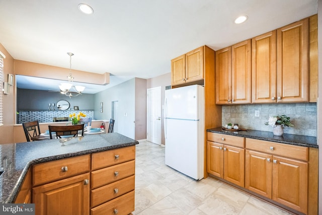 kitchen with decorative backsplash, brown cabinets, pendant lighting, and freestanding refrigerator