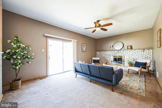 living area with visible vents, a brick fireplace, baseboards, carpet flooring, and a ceiling fan