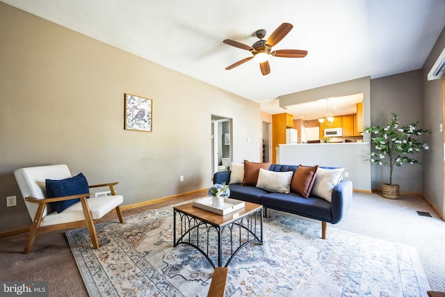 living room with visible vents, ceiling fan with notable chandelier, baseboards, and carpet floors