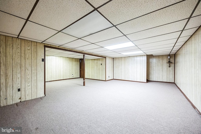 finished below grade area featuring carpet, wooden walls, and a paneled ceiling