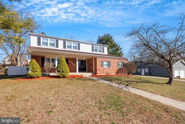 traditional-style house with brick siding, a front lawn, and fence