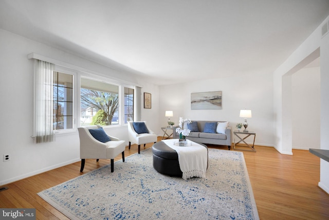 living room with light wood-type flooring, baseboards, and visible vents