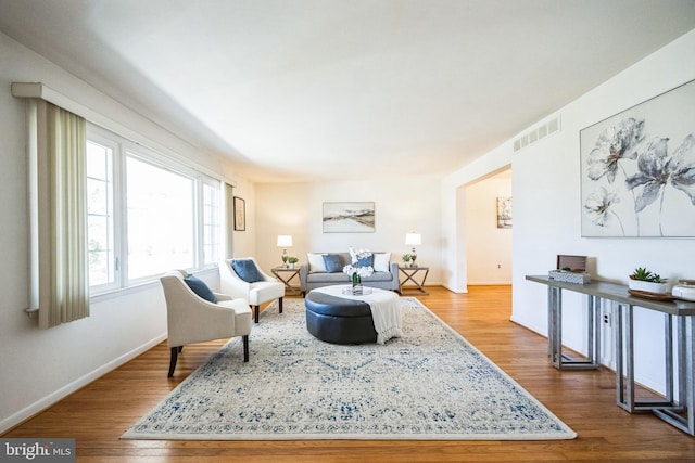 living room with wood finished floors, visible vents, and baseboards