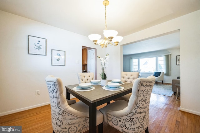 dining room with light wood-type flooring, baseboards, and a notable chandelier