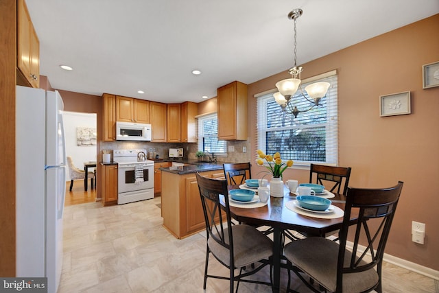 kitchen with white appliances, baseboards, a peninsula, a sink, and tasteful backsplash