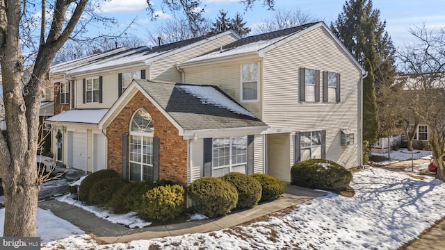 snow covered property with a garage