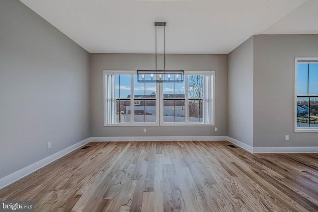 unfurnished dining area with light hardwood / wood-style floors and a notable chandelier