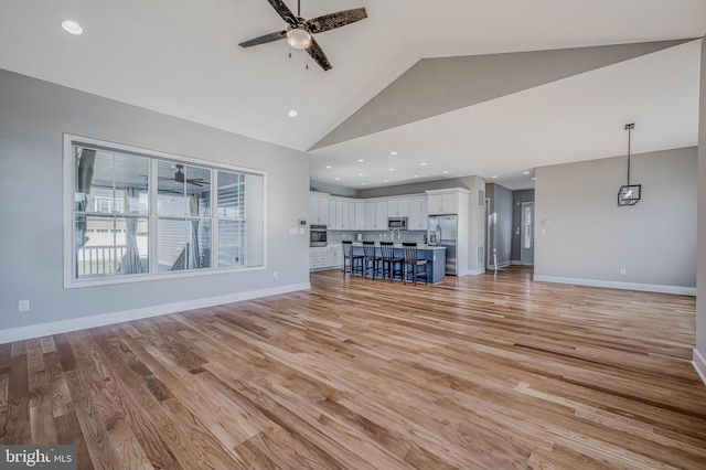 unfurnished living room featuring high vaulted ceiling, ceiling fan, and light wood-type flooring