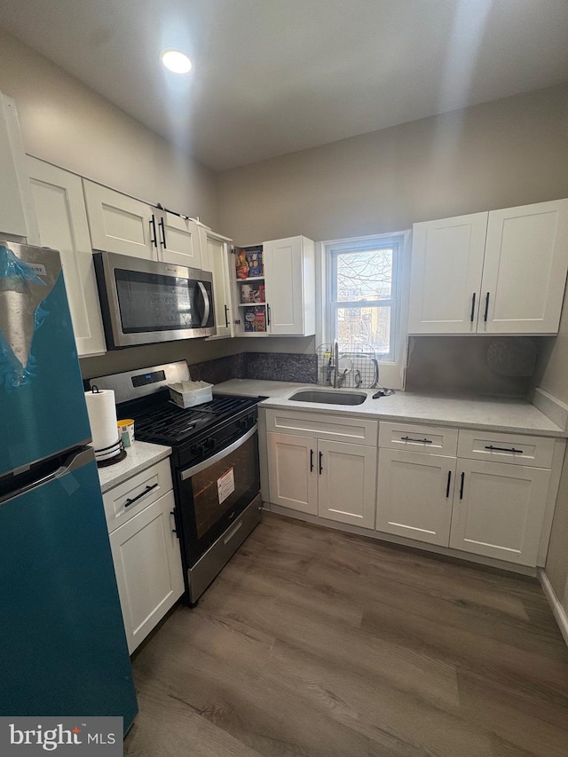 kitchen with stainless steel appliances, white cabinetry, and sink