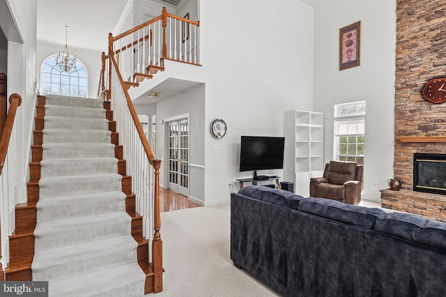 living room featuring plenty of natural light, a towering ceiling, a fireplace, and light hardwood / wood-style flooring