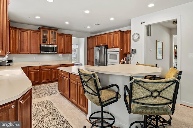 kitchen featuring stainless steel appliances, a kitchen island, light tile patterned floors, and a kitchen bar