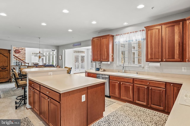 kitchen with stainless steel dishwasher, sink, hanging light fixtures, and a wealth of natural light