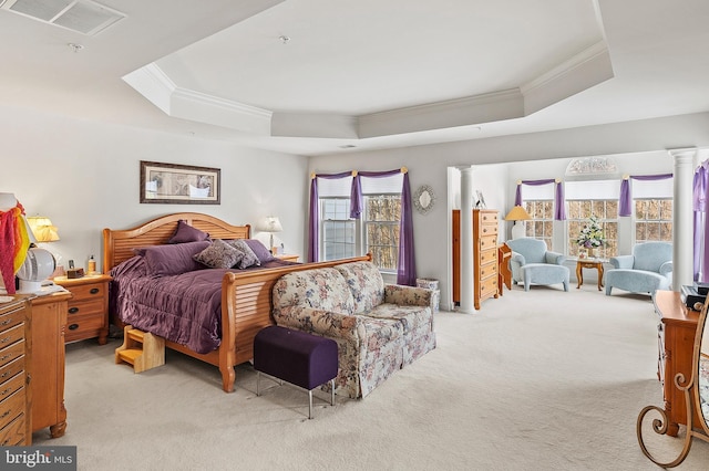 bedroom with decorative columns, ornamental molding, light colored carpet, and a tray ceiling