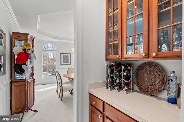 bar featuring ornamental molding, a raised ceiling, and light carpet