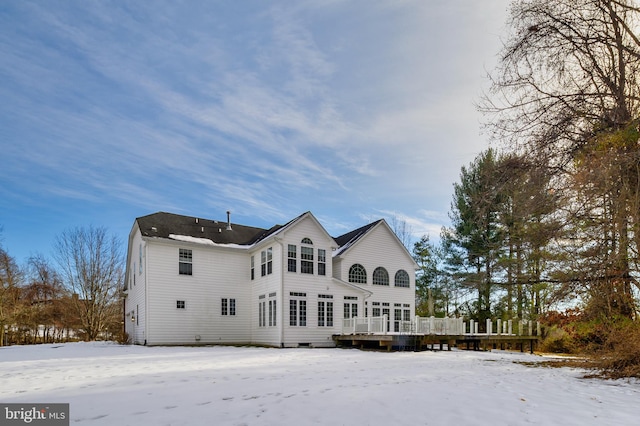 snow covered house featuring a wooden deck