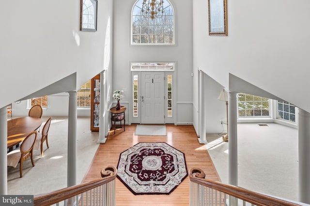 foyer with light hardwood / wood-style floors, a high ceiling, and ornate columns