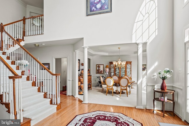 entryway featuring decorative columns, crown molding, and hardwood / wood-style flooring