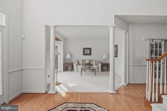 foyer with ornamental molding, light hardwood / wood-style flooring, and ornate columns