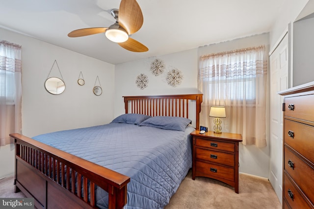 bedroom with ceiling fan, light colored carpet, and multiple windows