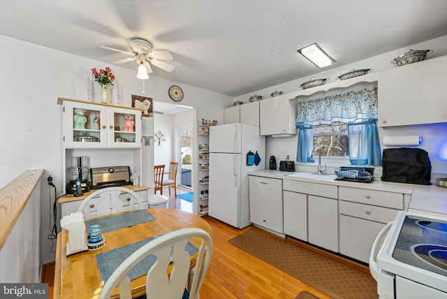 kitchen featuring sink, white appliances, light hardwood / wood-style flooring, ceiling fan, and white cabinets