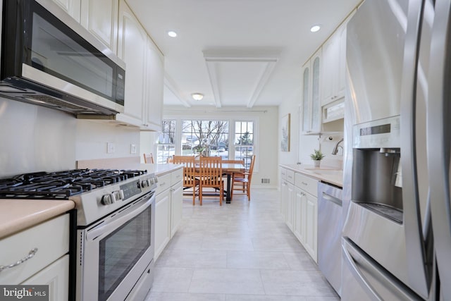 kitchen with a sink, stainless steel appliances, white cabinets, and light countertops