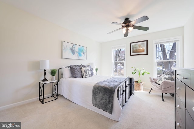 bedroom featuring light colored carpet, baseboards, and ceiling fan