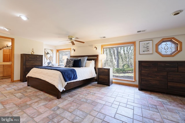 bedroom featuring stone finish floor, baseboards, visible vents, and ceiling fan