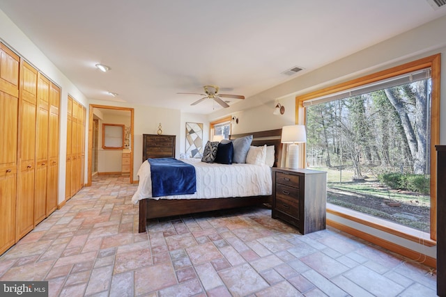 unfurnished bedroom featuring visible vents, baseboards, a ceiling fan, and stone finish flooring