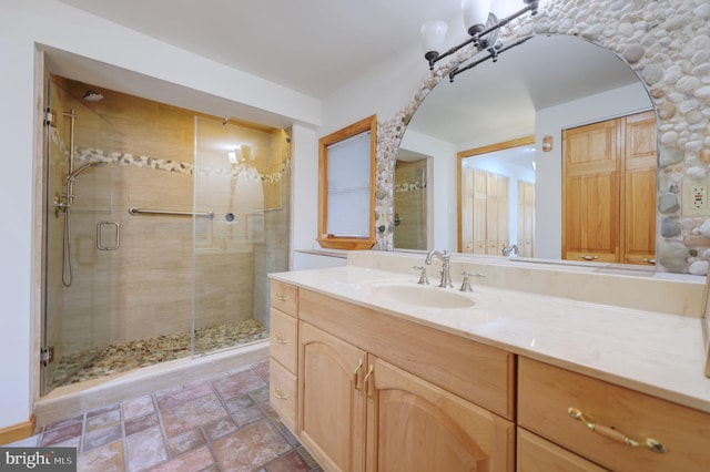 bathroom featuring stone tile floors, a shower stall, and vanity