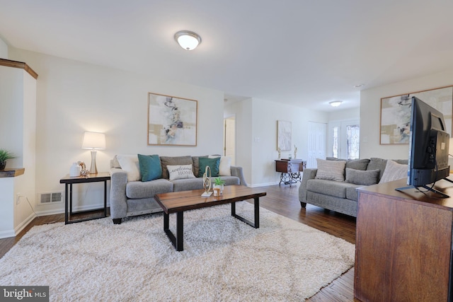 living area with wood finished floors, visible vents, and baseboards