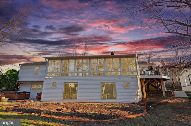 rear view of property with a wooden deck, stairway, a hot tub, and a sunroom