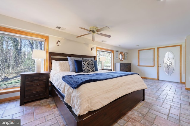 bedroom with stone tile floors, visible vents, and baseboards