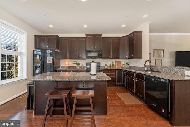 kitchen featuring dark wood-type flooring, sink, kitchen peninsula, light stone countertops, and black appliances