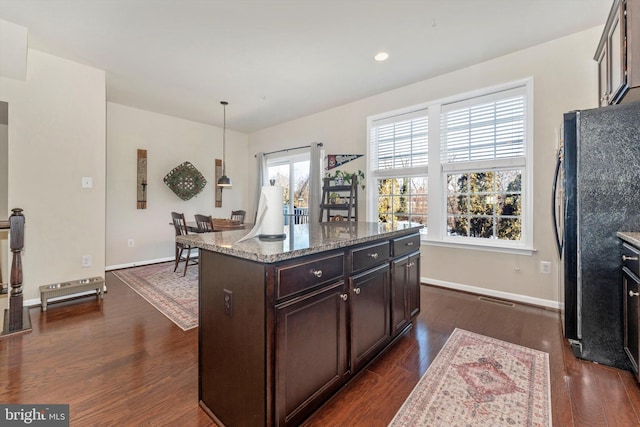 kitchen with a kitchen island, black fridge, dark brown cabinetry, and decorative light fixtures