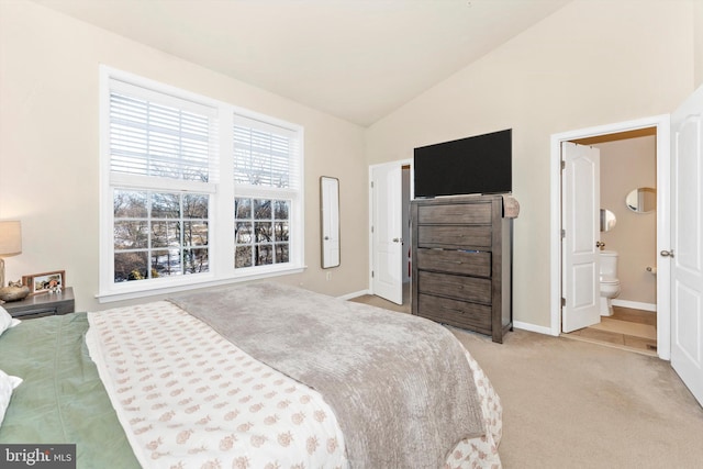 carpeted bedroom with ensuite bath and vaulted ceiling