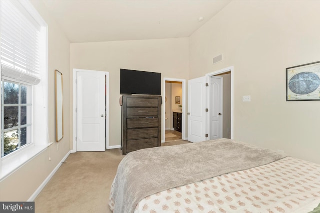 bedroom featuring light colored carpet and high vaulted ceiling