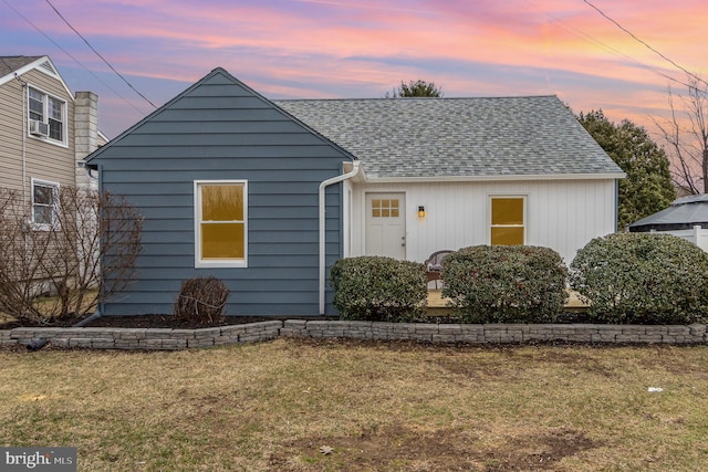 view of front of property with a shingled roof and a front lawn