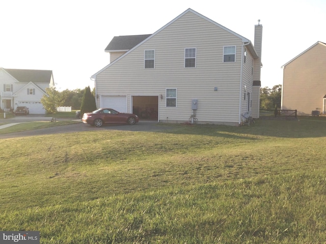 rear view of house featuring a yard and a garage