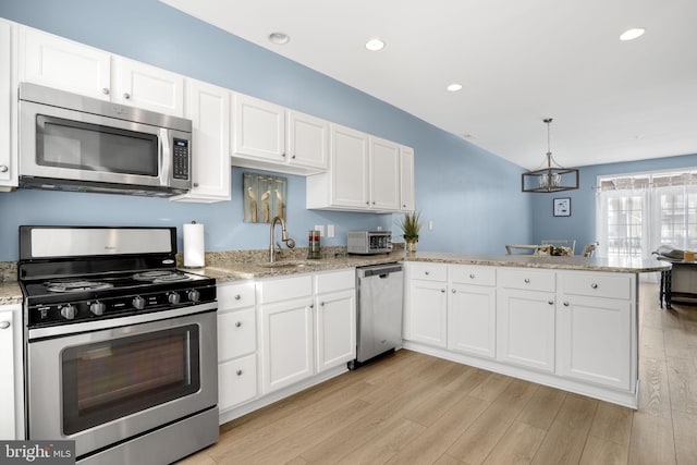 kitchen featuring stainless steel appliances, white cabinets, light wood-style flooring, and a peninsula