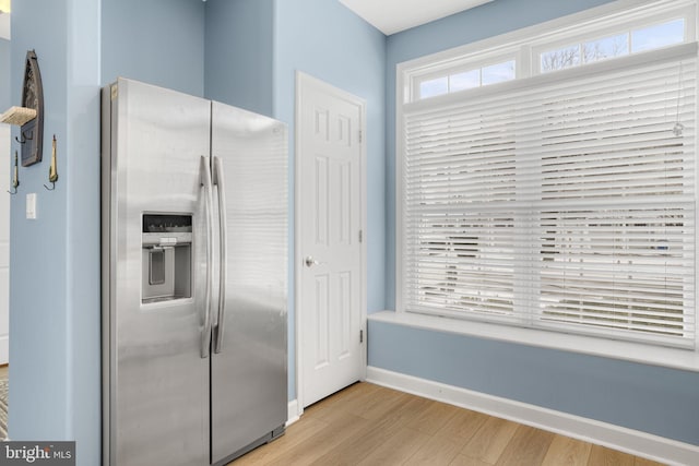 kitchen with light wood-type flooring, baseboards, and stainless steel refrigerator with ice dispenser