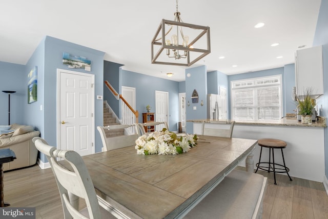 dining room featuring recessed lighting, light wood-style flooring, an inviting chandelier, and stairs