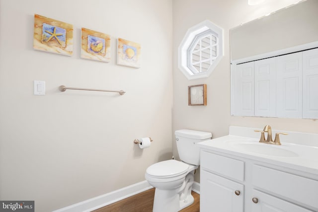 half bath featuring toilet, baseboards, wood finished floors, and vanity