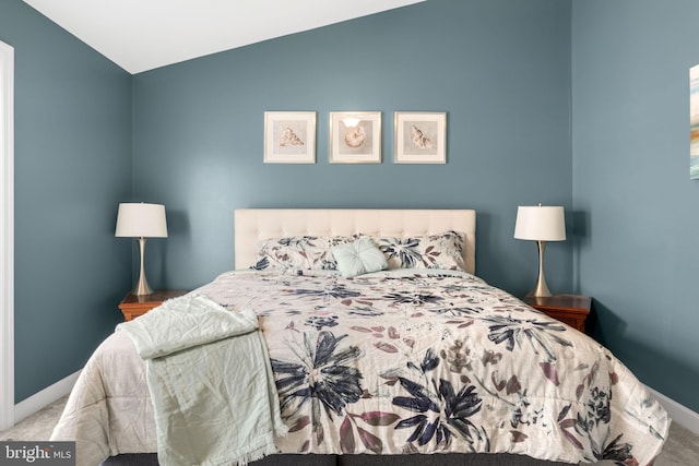 bedroom featuring lofted ceiling, baseboards, and carpet